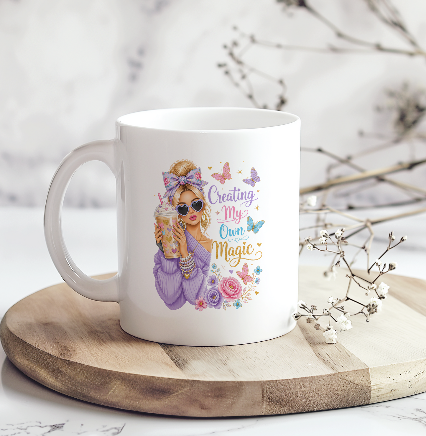 White ceramic coffee mug featuring a stylish woman with sunglasses holding an iced coffee, surrounded by butterflies and flowers with the inspirational quote "Creating My Own Magic."