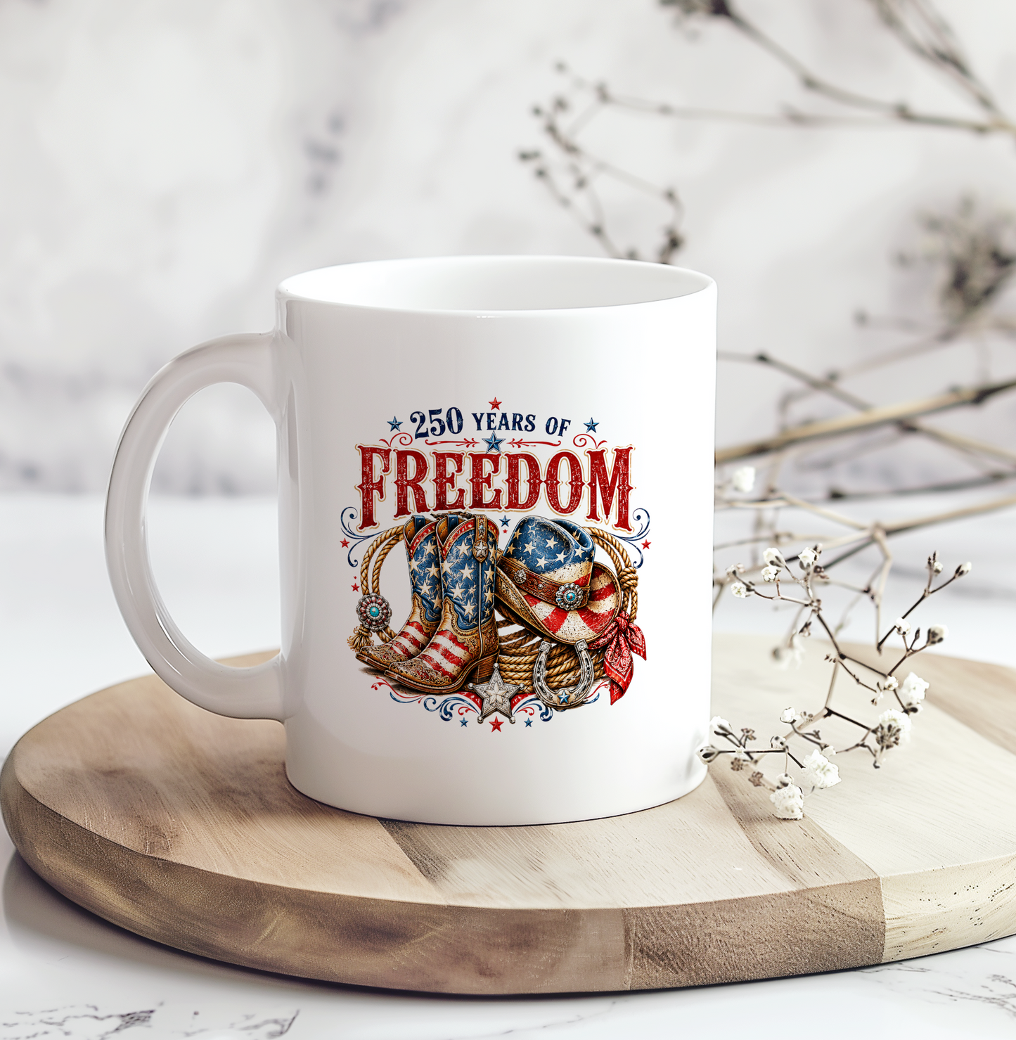 White ceramic coffee mug featuring a vintage patriotic western design with cowboy boots, cowboy hat, horseshoes, rope, and the phrase "250 Years of Freedom," making it a unique America 250 patriotic gift.