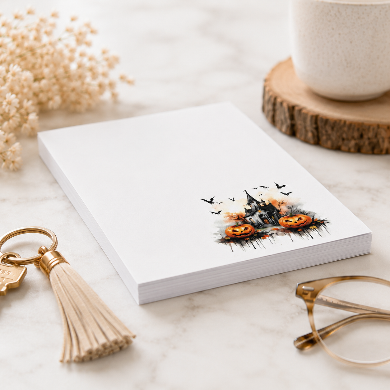 White Halloween notepad featuring a haunted house, smiling pumpkins, bats, and autumn accents in the lower corner.