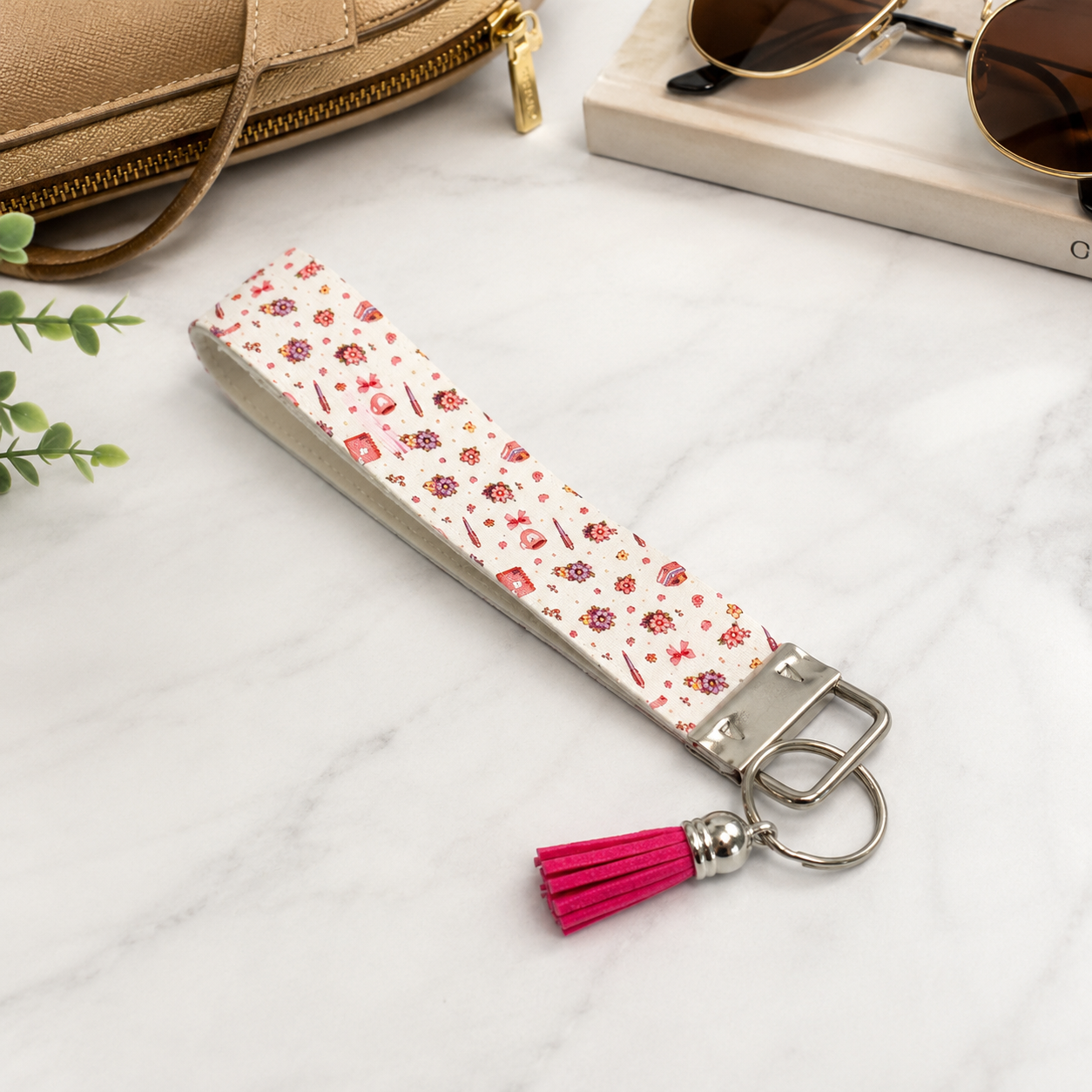 Pink floral fabric wristlet keychain with silver hardware and bright pink tassel displayed on a neutral background.