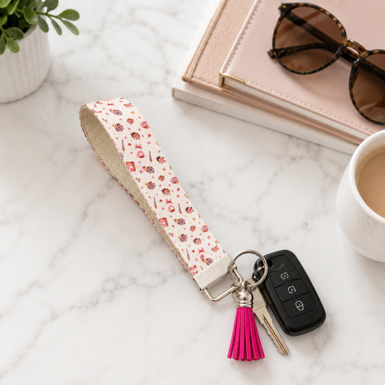 Pink floral fabric wristlet keychain with silver hardware and bright pink tassel displayed on a neutral background.