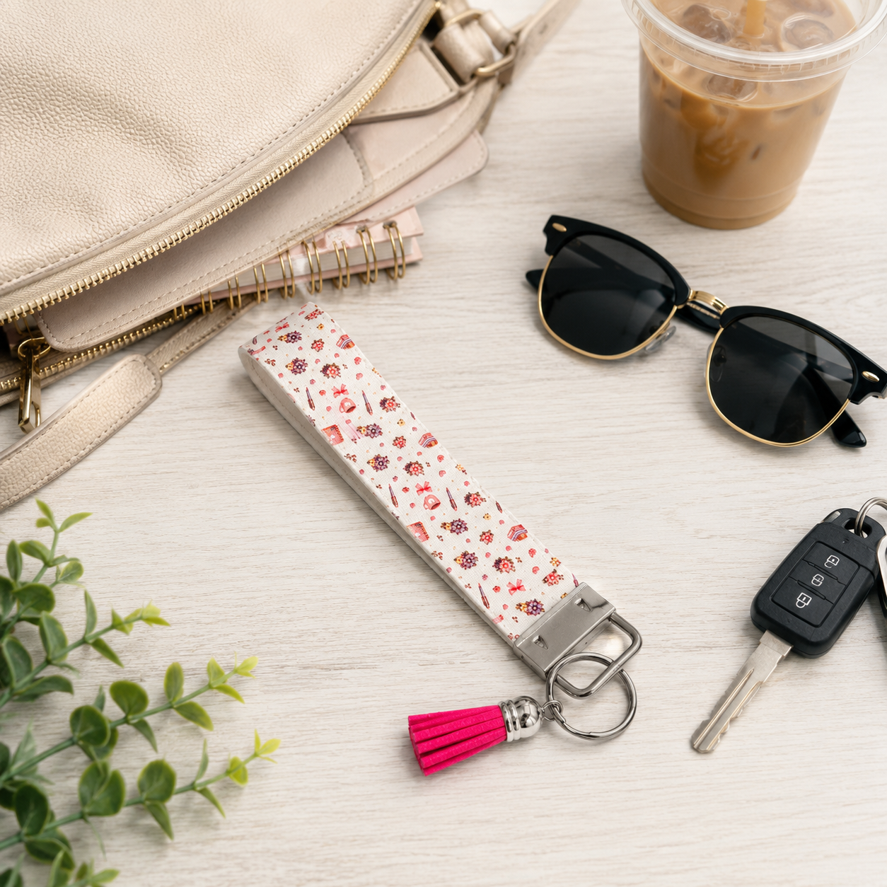 Pink floral fabric wristlet keychain with silver hardware and bright pink tassel displayed on a neutral background.