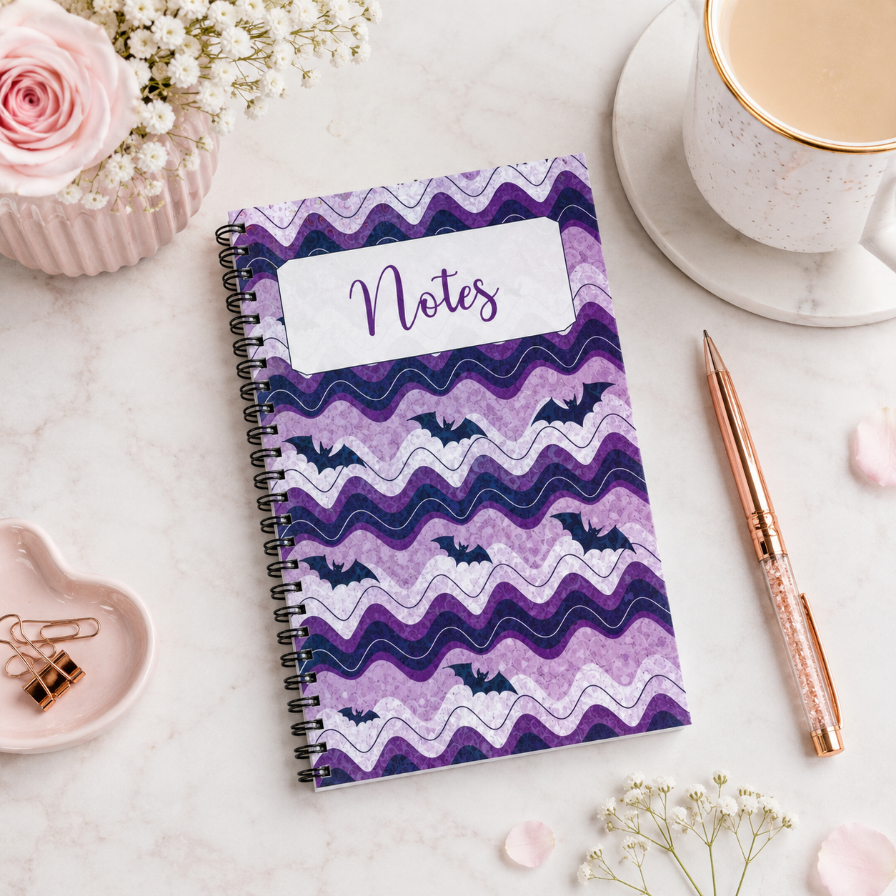 Purple spiral-bound notebook featuring whimsical bat artwork and wavy lavender patterns, perfect for notes, journaling, planning, and everyday writing.