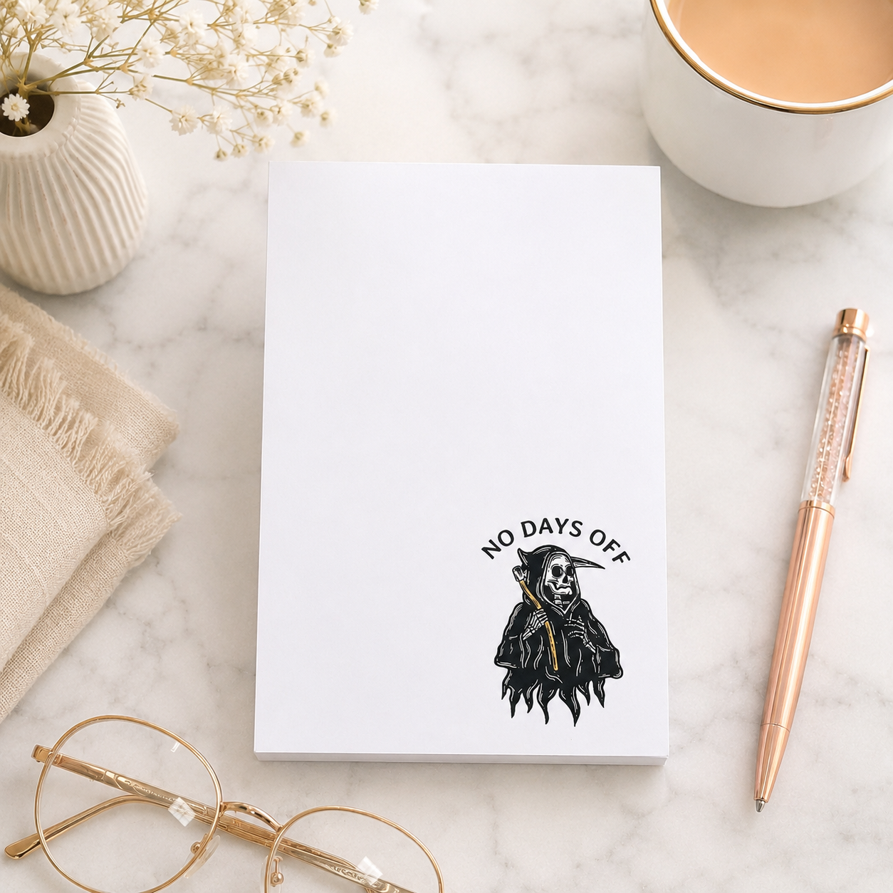 White notepad featuring a small grim reaper illustration and the words "No Days Off" in a minimalist dark humor design for notes, lists, and reminders.
